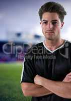 serious soccer player with hand folded and black t-shirt, field blurred background