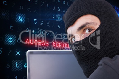 Cyber criminal wearing a hood uses a laptop against website code background