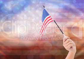 Hand with American flag with sparkling light bokeh background