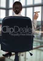 Back of seated business woman smoking cigar in blurry office