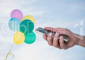 Hand with phone against sky and balloons