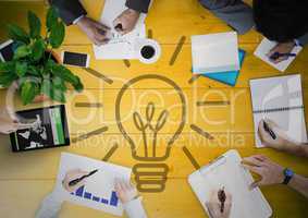 Overhead of business team with yellow wood panel and lightbulb graphic