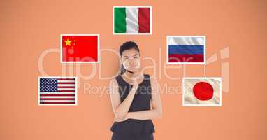 Portrait of beautiful woman holding pen standing by flags against orange background