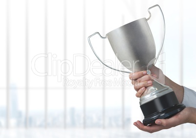 Business hand holding trophy against window