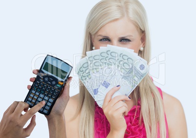 Cropped hands using calculator and beautiful woman holding currencies standing against white backgro