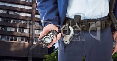 Midsection of security guard holding radio in city