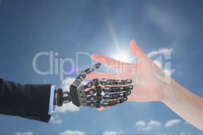 human hand is touching robot hand against sky background