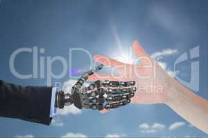 human hand is touching robot hand against sky background