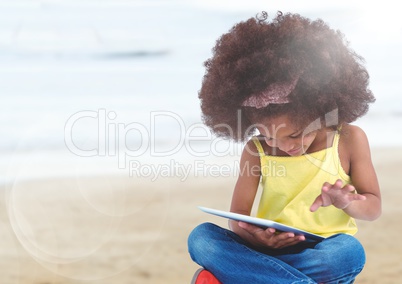 Girl with tablet against blurry beach with flare