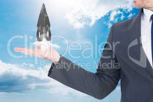 Businessman is holding rocket taking off from his hand against sky background