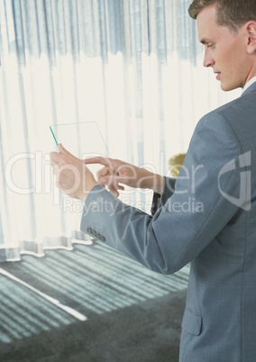 Businessman touching phone in office by window light