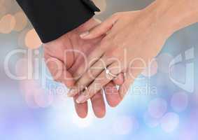 Hands holding together wedding engagement ring with sparkling light bokeh background