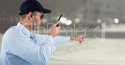 Security guard with walkie talkie pointing against blurry street
