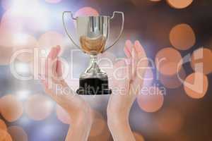 Hands holding trophy against orange glowing background