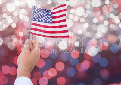 Hand holding American flag with sparkling light bokeh background