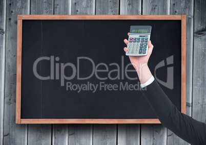 Hand with calculator against chalkboard and grey wood panel