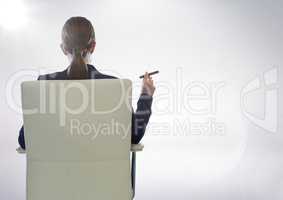 Back of seated business woman smoking cigar against white background with flare