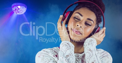 Happy casual woman listenning music with headphones in front of blue background with a disco ball