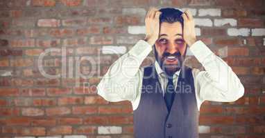 Worried hipster man with his hands on his head in front of a red wall