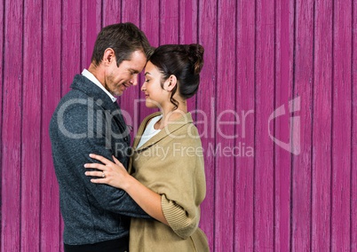 couple huging and looking each other with pink wood background