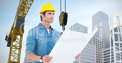 Labourer with plans watching ahead close to a crane