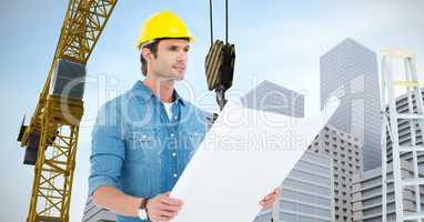 Labourer with plans watching ahead close to a crane