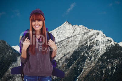 Red-hair woman smiling to the photo  in front of snow-covered mountains background