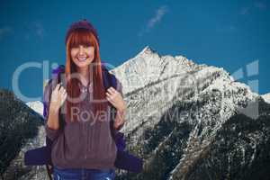 Red-hair woman smiling to the photo  in front of snow-covered mountains background