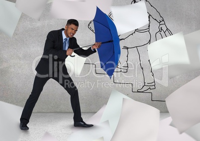 Businessman holding blue umbrella amidst flying papers against graffiti wall