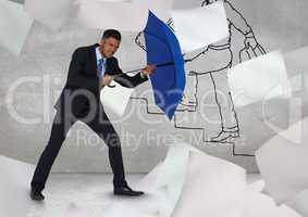 Businessman holding blue umbrella amidst flying papers against graffiti wall
