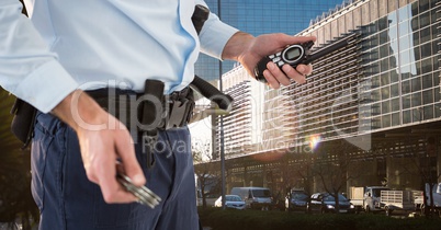 Mid section of security guard holding keys and walkie talkie while standing in city