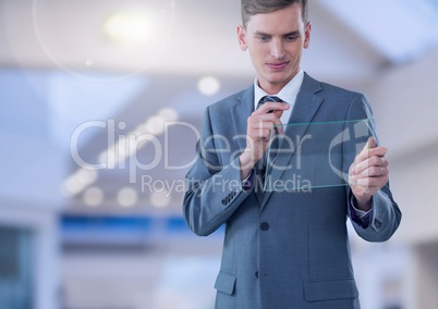 Businessman holding glass screen in large bright space
