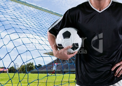 soccer player with the ball on his arm in front of the goal