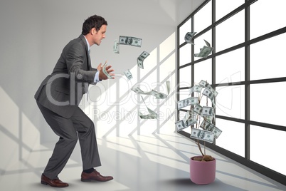 businessman is looking at falling money from a tree against office background