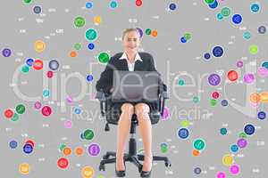 Businesswoman seated with a laptop in front of a digital background