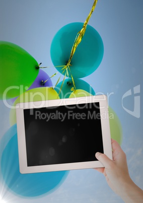 Hand with tablet against baloons and flare