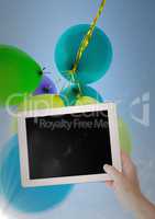 Hand with tablet against baloons and flare