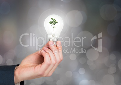 Hands  holding lightbulb with green nature energy with sparkling light bokeh background