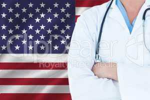 doctor with crossed arms holding a stethoscope against american flag background