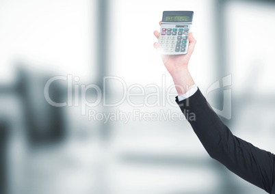 Hand with calculator against blurry grey office