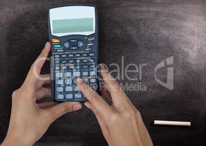 Hands with calculator against chalkboard