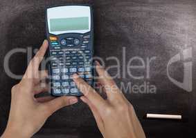 Hands with calculator against chalkboard