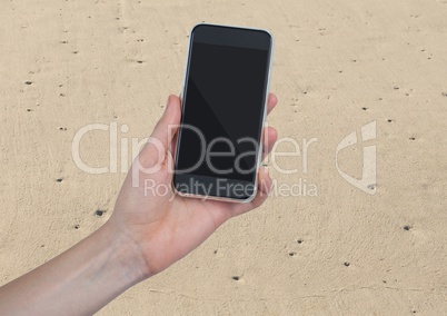 Hand with phone against sand