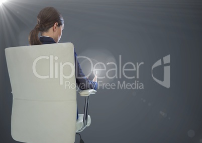 Back of seated business woman with phone against grey background with flares