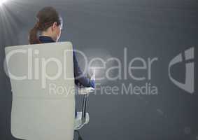 Back of seated business woman with phone against grey background with flares