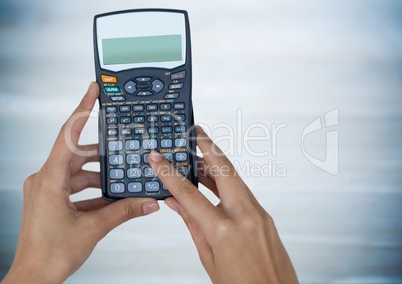 Hands with calculator against blurry blue wood panel