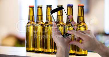 Hand taking picture of beer bottles through smart phone