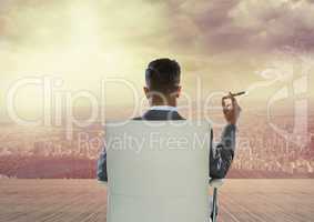 Rear view of businessman sitting on chair and smoking cigar while looking at city