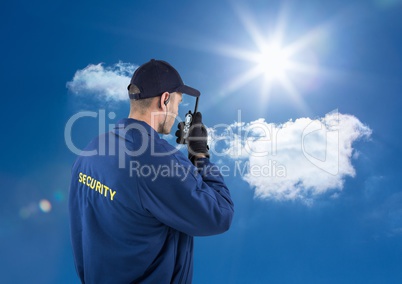 Rear view of security guard talking on walkie talkie against sky