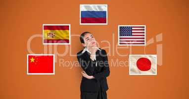 Thoughtful businesswoman standing by flags against orange background